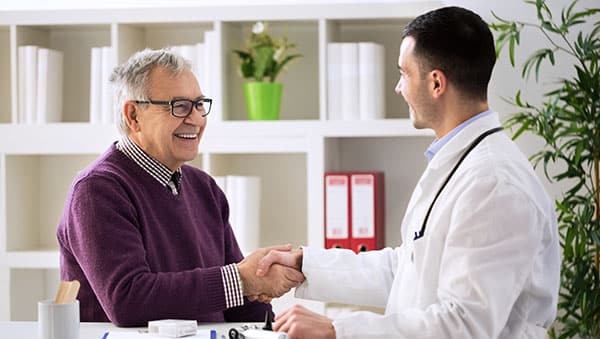 Young doctor congratulating senior patient on recovery